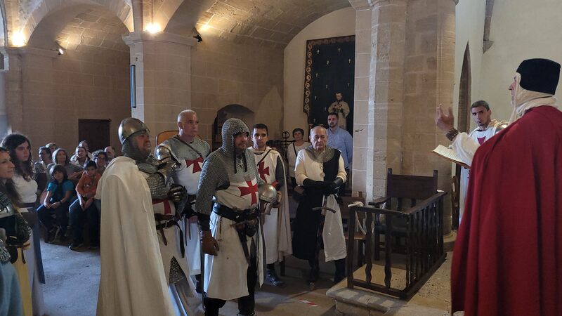 Formació dins una església de pedra durant una cerimònia, amb públic assegut als costats.