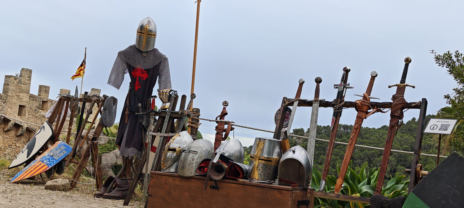 Parada d'armes vora el castell de Capdepera: un maniquí amb cota de malla, espases, elms i escuts pintats.