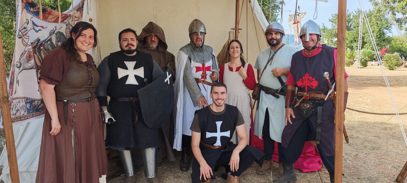 El grup posant somrient davant una tenda del campament, amb cotes de malla i vestits d'època.